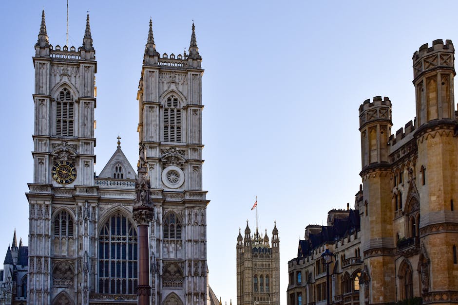 A detailed view of Westminster Abbey's façade showing Gothic architecture with pointed spires and ornate stone carvings. The image captures the large, circular stained glass rose window at the center